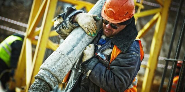 Construction worker in safety gear handling equipment on an active site., tags: und - pexel